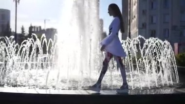 Güzel model kız ile güzel bir çeşme kenarında yürüyüş vurgulamaktadır. HD, 1920 x 1080. ağır çekim.