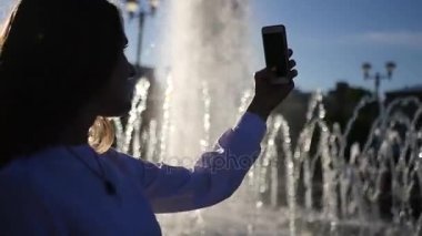 Uzun saçlı güzel bir kız, çeşme ile arka plan bulanık fotoğraf ayakta yapar. HD, 1920 x 1080. ağır çekim.