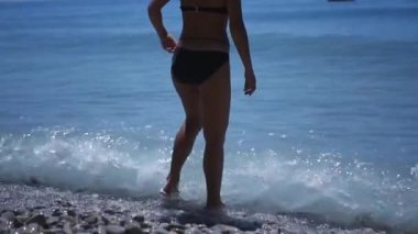 Bir mayo içinde ince bir kız suda duruyor, dalgalar bacaklarını karşı darbeleme. HD, 1920 x 1080. ağır çekim.