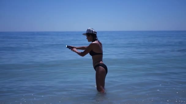 Mince fille debout dans l'eau prenant des photos de la mer. HD, 1920 x 1080. au ralenti . — Video