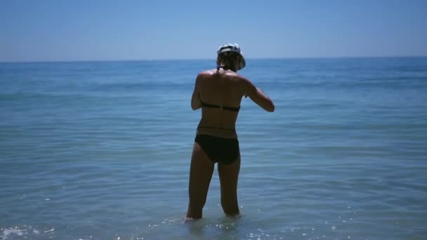 年轻的女孩站在海水中, 看着东西和拍照。Hd, 1920x1080。慢动作. — 图库视频影像
