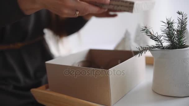 Woman packs gifts for new year, christmas presents for children, souvenirs and toys for holidays, packaging the parcel before departure — Stock Video