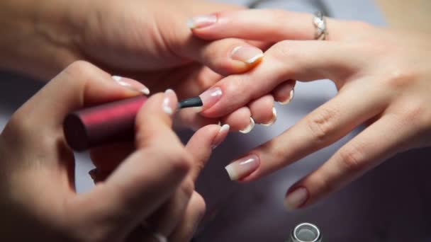 Maestro de manicura cubre las uñas de las mujeres por esmalte de uñas transparente, la mujer viene al salón de manicura, cuidado de las uñas, negocio en belleza — Vídeo de stock