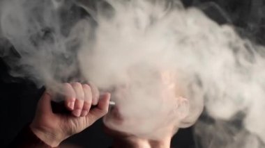 Adam elektronik sigara içiyor ve ve bazı duman bulutları yapar biri vaping, e-cig ve vape kalem, insanların kötü alışkanlıkları