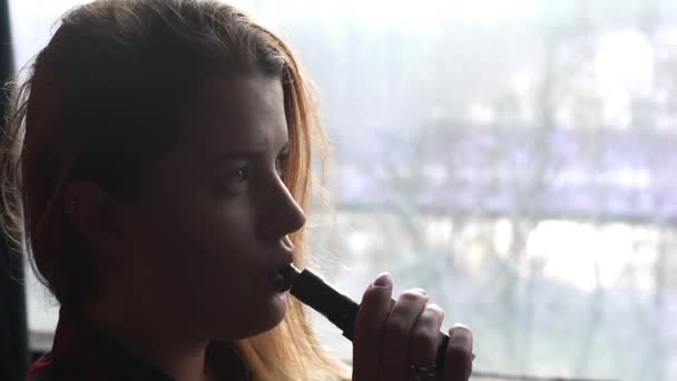 Mulher bonita fuma cigarro eletrônico e faz nuvens de fumaça, adolescente é vaping, e-cig e caneta vape, maus hábitos de pessoas — Vídeo de Stock