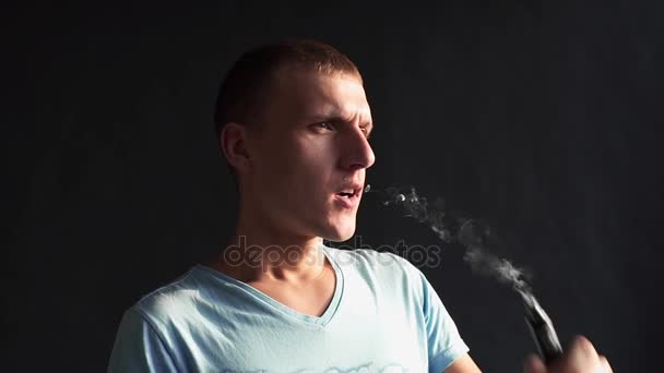 Чоловік курить електронну сигарету і робить димові хмари, хлопець вейпінг, електронні цигарки та вейп-ручка, шкідливі звички людей — стокове відео