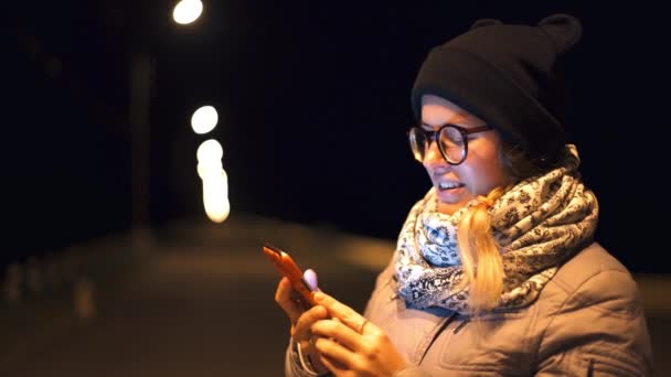 Mujer recibe llamada telefónica en su teléfono inteligente en la noche al aire libre, gadgets en la vida de las personas, comunicaciones inalámbricas, emociones por teléfono — Vídeo de stock