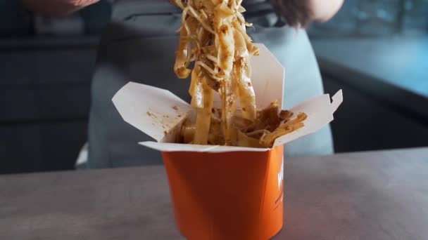 Femme mélange des nouilles asiatiques dans une boîte par baguettes, cuisine panasiatique, nouilles frites aux fruits de mer, repas épicés, WOK — Video