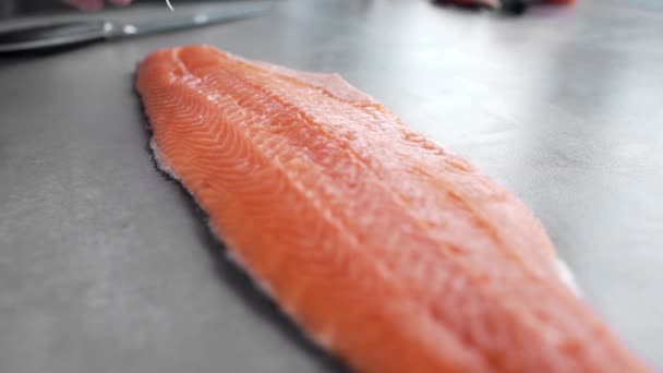 Шеф-повар вынимает кости из филе лосося, режет рыбу, блюда с рыбой, диетическую пищу, здоровое приготовление пищи, на кухне — стоковое видео