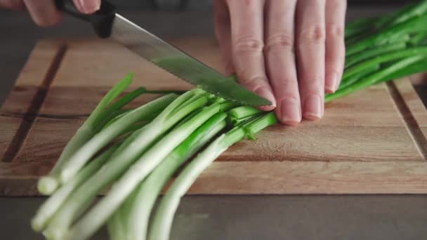 Γυναίκα φέτες το πράσινο κρεμμύδι στην ξύλινου σκάφους στην κουζίνα, χόρτα από τον κήπο, το καλοκαίρι βιταμίνες, χρήσιμο υλικό — Αρχείο Βίντεο