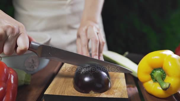 Повар режет баклажаны на деревянной доске снаружи для приготовления вегетарианской еды, овощной кухни, веганской пищи, приготовления пищи — стоковое видео