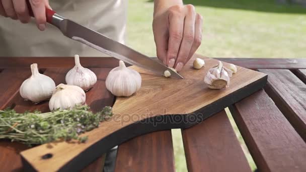 Kucharz plasterki czosnku na desce przez ostry nóż poza, gotowania na zewnątrz, gotowanie zdrowe jedzenie, posiłki latem — Wideo stockowe