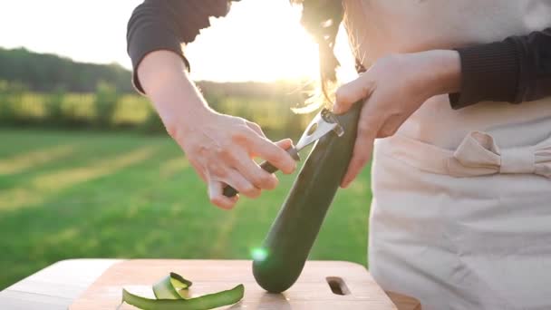 La cuoca affetta zucchine alla luce del tramonto all'esterno, cucinando sul fuoco aperto, cibo vegetariano, pasti sani e dietetici, vitamine nel cibo, cucinare all'aperto — Video Stock