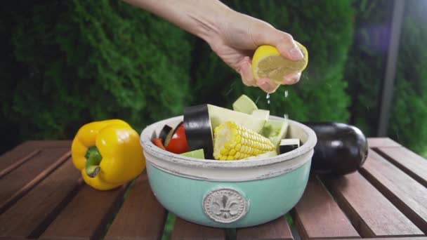 De samendrukking van de chef-kok uit citroensap toe aan de kom met vers gesneden fruit, vruchtensap, salade, eten koken buitenshuis, vegetarische maaltijd maken — Stockvideo