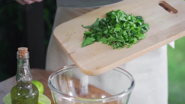 O cozinheiro espalha a salsa picada para a tigela de vidro ao ar livre, comida cozinhando fora, vitaminas em alimentos saudáveis, verdes frescos do próprio jardim — Vídeo de Stock