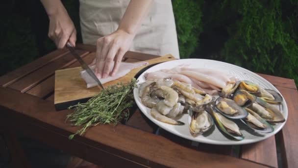 Кухар нарізає сирі кальмари на дерев'яній дошці, шеф-кухар готує морепродукти для приготування азіатської кухні, готує на відкритому повітрі — стокове відео