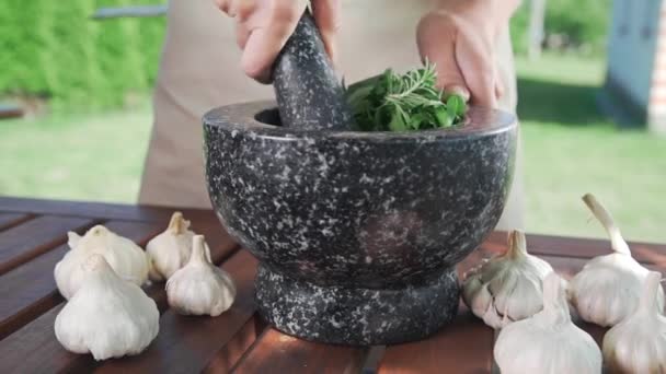 Домохозяйка измельчает чеснок и петрушку для пряного натурального соуса снаружи, приготовление пищи, пряная пища, вегетарианская еда, зелень и салаты — стоковое видео