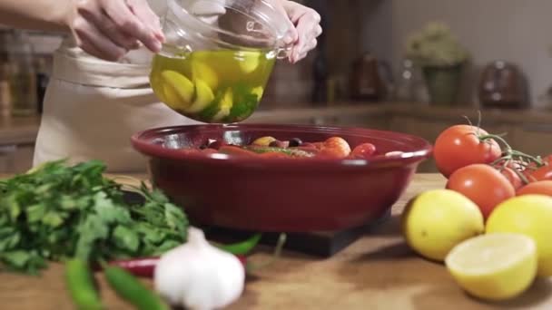 O cozinheiro faz prato vegetariano com caldo quente e legumes frescos, cebola com alho, limões e verduras, prato vegetal em tazhin — Vídeo de Stock