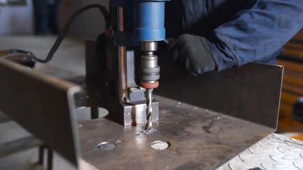 Le travailleur perçage la tôle par perceuse, coupe de métal avec beaucoup d'étincelles, étincelles métalliques, travailleur sur l'usine, métallurgie à l'usine 