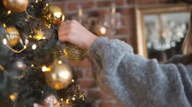 Genç çekici beyaz kadın kış tatilleri için altın toplar, Noel arifesi, x-mas düzenlemeler, çelenk ve dekor tarafından Noel ağacı süsle