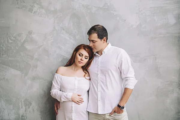 Happy future parents are waiting for baby, married couple is waiting for a child, pregnant woman with red long hair, beauty of pregnancy, love and support in family