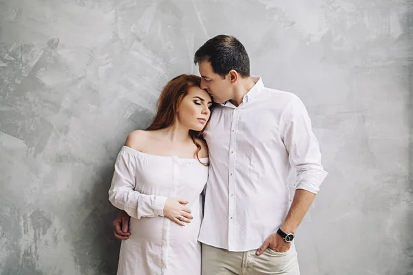Happy future parents are waiting for baby, married couple is waiting for a child, pregnant woman with red long hair, beauty of pregnancy, love and support in family