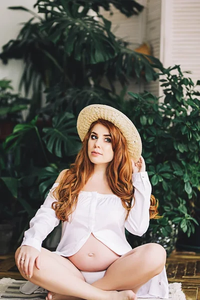 Mulher grávida bonita com cabelos longos vermelhos em camisa branca longa, beleza da gravidez, esperando por uma criança, futuros pais, tornando-se uma mãe, nova vida — Fotografia de Stock