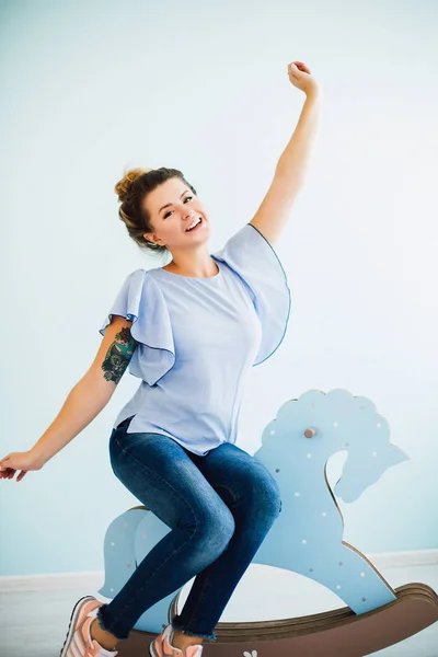 Kıvırcık saçlı ve mavi gözlü kadın ile therocking at ve gülümsüyor, beyaz kız, kadın portre, mutluluk ve sevinç gülümseyen mutlu çekici kız oturuyor