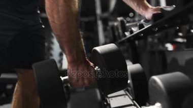 Güçlü adam fitness kulübünde spor salonu, güç egzersizleri dumbbells ile atlet kaslara pompalıyor, sakallı beyaz adam pazı pompalıyor