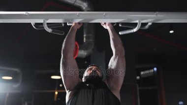 Güçlü adam fitness kulübünde spor salonu, güç egzersizleri simülatörleri, pull-up yatay bir çubuk üzerinde atlet kaslara pompalıyor, sakallı beyaz adam kas pompalama