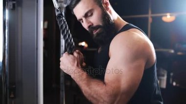 Güçlü adam fitness kulübünde spor salonu, güç egzersizleri simülatörleri, atlet kaslara pompalıyor, sakallı beyaz adam kas pompalama