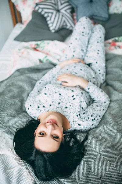 Happy beautiful pregnant caucasian woman with big belly in pajamas in the bedroom, future parrents, waiting for a child, motherhood and care — Stock Photo, Image