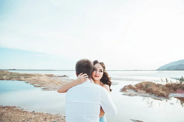 Aşık genç çift göl kenarında dinlenme birlikte ve Dağları, güzel beyaz kadın ve adam düştü sevgi, şefkat ve hugs, güzel arka planı düz çift