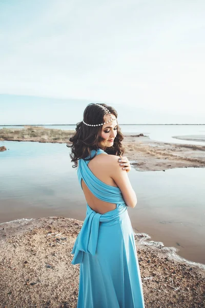 Portrait of the attractive caucasian woman with long dark hair, pretty girl in the blue dress and with diadem in the hair against the beautiful background of the landscape, woman near the lake and — Stock Photo, Image