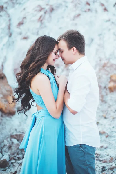 Young couple in love is resting together near the lake and mountains, beautiful caucasian woman and man fell in love, tenderness and hugs, straight couple against the beautiful background of the