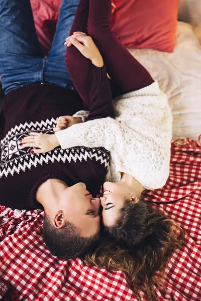 Kazak giymiş çift öpüşme ve sarılma mutlu Noel ağacının yanında rahat bir atmosfer ve aşk, ev ve aile, beyaz çift, evli insanlar