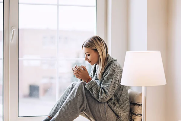 Rahat İskandinav interrior güzel beyaz şık kadın evde oturur büyük pencere, güzel kız, moda portre, şık kadın portresi