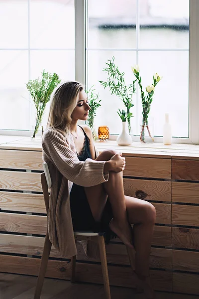 Güzel beyaz şık bir kadınla uzun Malaysian bacaklar rahat İskandinav interrior evde, güzel kız, moda portre, şık kadın portresi oturur