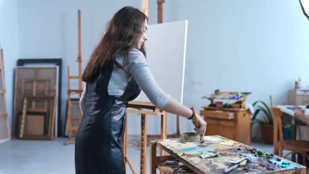 Artista dipinge un dipinto con passione in uno studio, pittore al lavoro, creatore fa opera d'arte, tela, pennelli e vernici — Video Stock