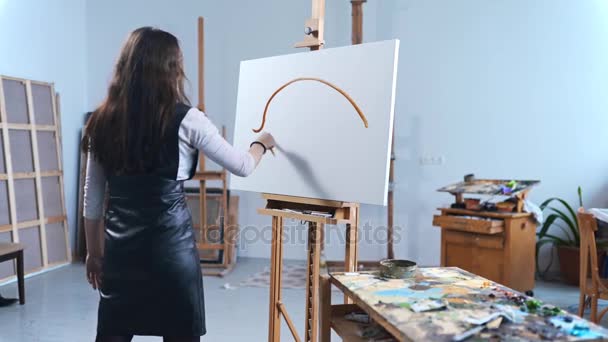 Konstnär målar en tavla med passion i en studio, målare på jobbet, creator gör bit av konst, duk, penslar och färger — Stockvideo