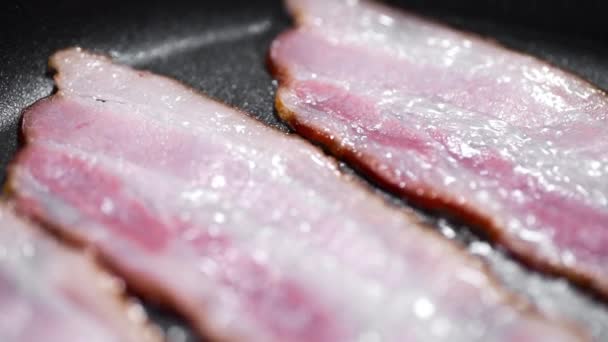 Des morceaux de bacon savoureux sont frits sur la poêle chaude, graisse bouillante chaude, cuisson de la viande, repas avec de la viande, bacon pour le petit déjeuner, viande de porc — Video