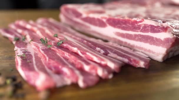 O cozinheiro polvilha bacon cru pelo tomilho cortado, carne de cozinha, refeições com produtos de carne, porco de cozinha — Vídeo de Stock