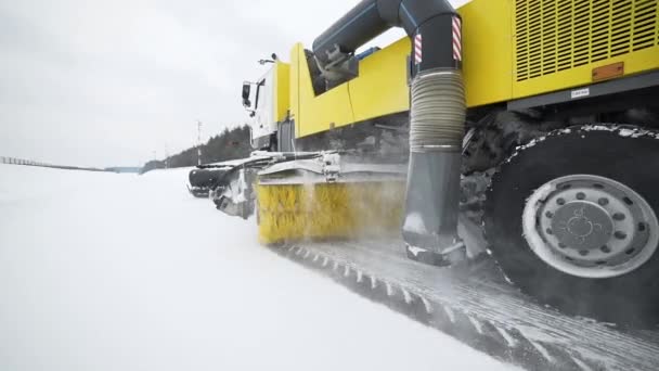 Heavy wheel machinery removes snow from the road with big massive rotating brush in the snowy weather, special machinery for roads cleaning, snow and ice removal, specialized truck — Stock Video