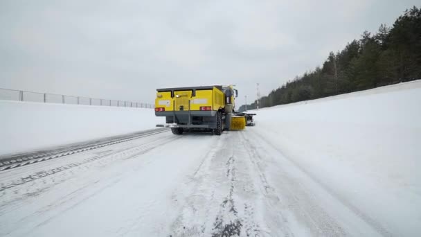 Сніг і лід видаляє сніг з дороги з великим відром і обертається пензлем у сніжну погоду, спеціальне обладнання для прибирання доріг, сніг і лід, спеціалізована вантажівка, колісні — стокове відео