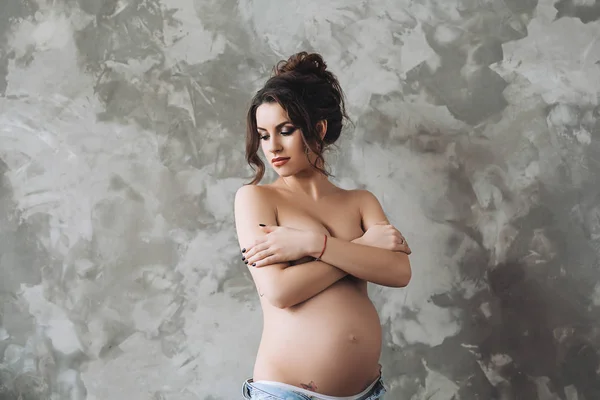 美しい魅力的な妊娠中の女性はトップレス立ち黒い髪、妊娠中の女性、セクシーな肖像画の美しさと妊娠中の白人女性の手によって彼女自身をカバー — ストック写真