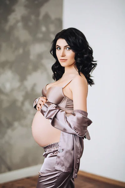 Krásná stylová těhotná žena s dlouhými tmavými vlasy drží její břicho, krása těhotenství, čeká dítě, budoucí rodiče, stát se matkou, nový život — Stock fotografie