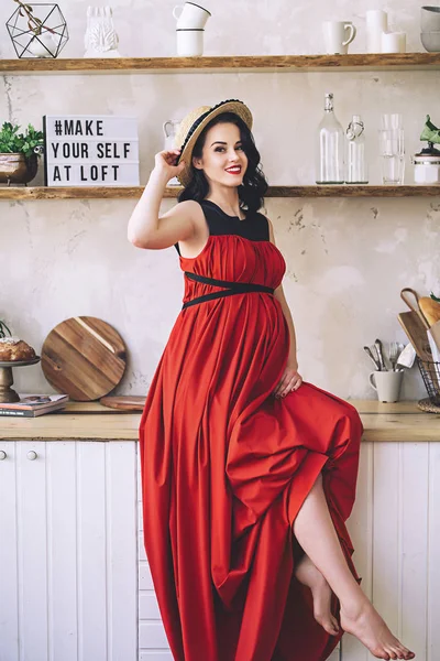 Retrato de moda de senhora grávida elegante atraente em sarafan vermelho longo e chapéu de palha, foto da mulher grávida feliz e bonita, tornando-se pais, roupas elegantes para a gravidez, futura mãe — Fotografia de Stock