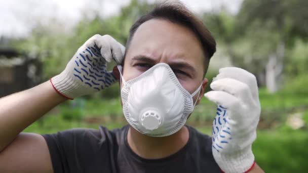 Man in working gloves puts on the resperator in slow motion outdoors, respiratory protection for human, security measures in paint works, personal protective equipment — Stock Video