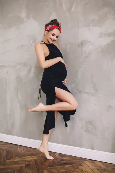 Πορτρέτο του το κομψό όμορφη έγκυος γυναίκα με μεγάλη κοιλιά και μακριά πόδια μαύρο μακρύ καλοκαίρι φόρεμα, μελλοντική μητέρα, περιμένοντας για ένα παιδί Εικόνα Αρχείου