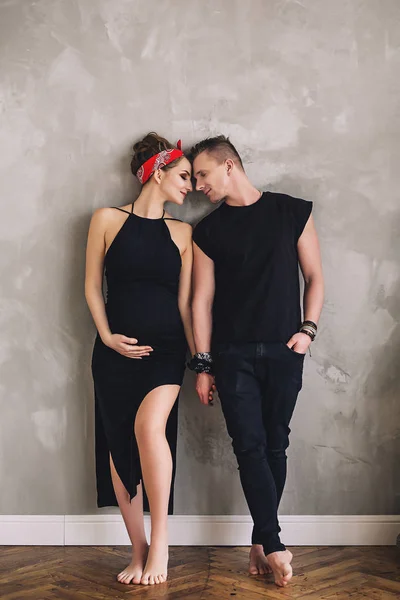 Frumos bărbat elegant și femeie însărcinată cu burtă mare în haine negre se uită unul la celălalt și se bucură de ei înșiși, viitoarele chirie, așteptând un copil — Fotografie, imagine de stoc